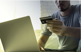 Pessoa com cartão em frente ao notebook